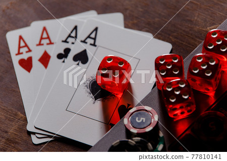 Red playing dice, gambling chips and cards with aces on a wooden table. Online casino theme Red playing dice, gambling chips and cards with aces on a wooden table. Online casino theme 77810141