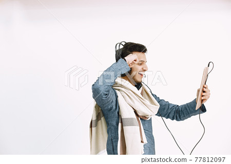 Indian man in headphones and tablet listening to music Indian man in headphones and tablet listening to music 77812097