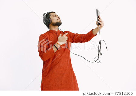 Indian man in headphones and tablet listening to music Indian man in headphones and tablet listening to music 77812100