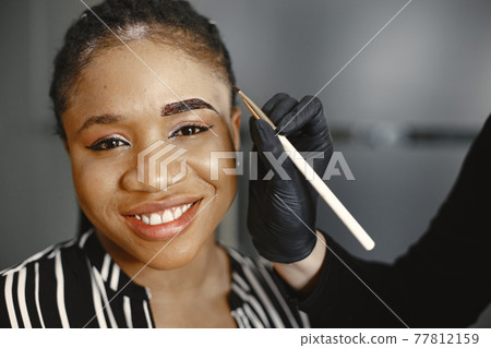 African girl doing eyebrow correction African girl doing eyebrow correction 77812159