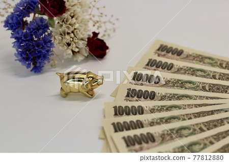 Dried flowers and golden pig figurines and a 10,000 yen note on a white background Dried flowers and golden pig figurines and a 10,000 yen note on a white background 77812880