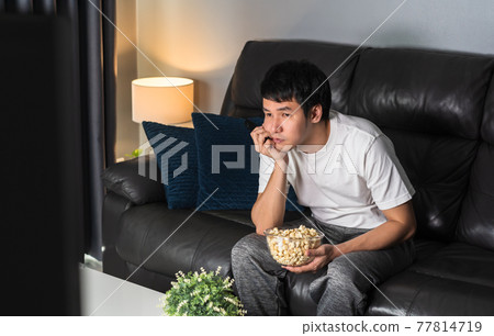 bored man watching TV on sofa at night bored man watching TV on sofa at night 77814719
