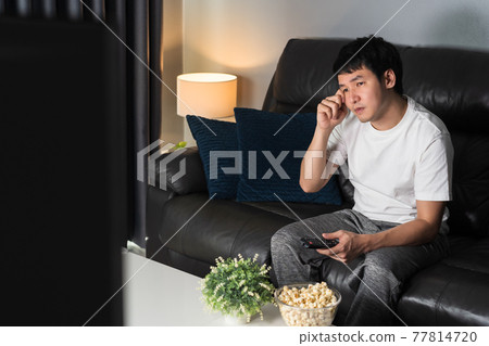 sad man watching television and crying on sofa at night sad man watching television and crying on sofa at night 77814720