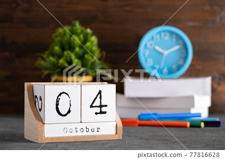 October 04th. October 04 wooden cube calendar with blur objects on background. October 04th. October 04 wooden cube calendar with blur objects on background. 77816628