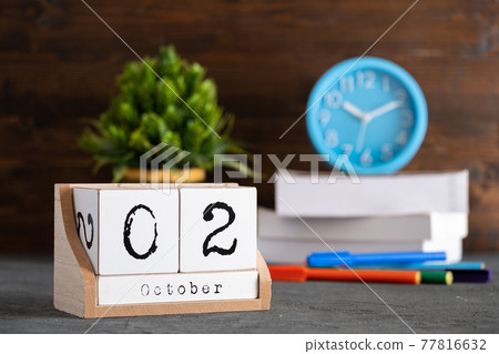 October 02nd. October 02 wooden cube calendar with blur objects on background. October 02nd. October 02 wooden cube calendar with blur objects on background. 77816632