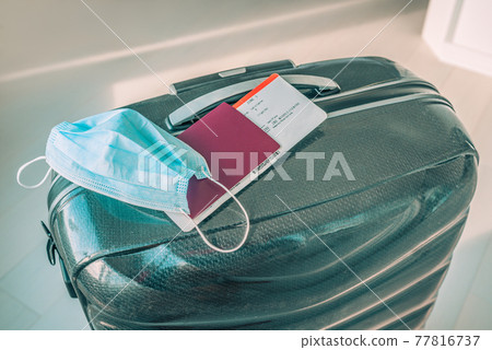 Travel restrictions during coronavirus pandemic depending of countries imposing quarantine or negative Covid-19 test at border. Face mask and passport over tourist luggage Travel restrictions during coronavirus pandemic depending of countries imposing quarantine or negative Covid-19 test at border. Face mask and passport over tourist luggage 77816737