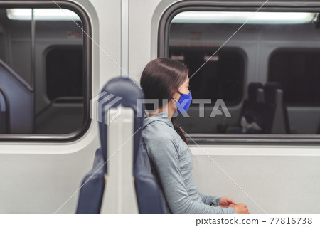 Woman pensive looking out the window during train commute wearing face mask in public transportation. Coronavirus pandemic lifestyle. Passenger commuter using cloth mouth covering Woman pensive looking out the window during train commute wearing face mask in public transportation. Coronavirus pandemic lifestyle. Passenger commuter using cloth mouth covering 77816738