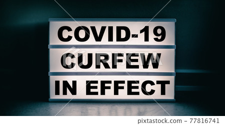 Curfew in effect text message on lit lightbox for covid coronavirus pandemic. Warning at night Curfew in effect text message on lit lightbox for covid coronavirus pandemic. Warning at night 77816741