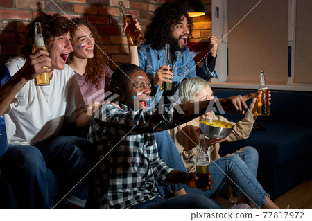 multi-ethnic group of people screaming yelling, fans having day-off resting eating popcorn and drinking beer 77817972