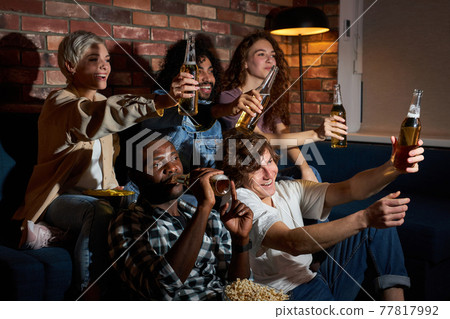 Excited student men and women supporting their favourite sport team, drinking beer, emotionally cheering Excited student men and women supporting their favourite sport team, drinking beer, emotionally cheering 77817992