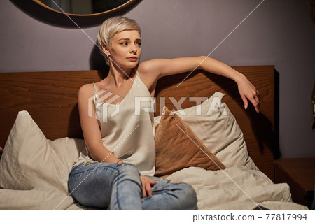 Worried female sit on bed alone having unhappy facial expression Worried female sit on bed alone having unhappy facial expression 77817994