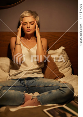Portrait Of Young Lady Suffering From Headache, Sitting On Bed At Home Alone 77817995