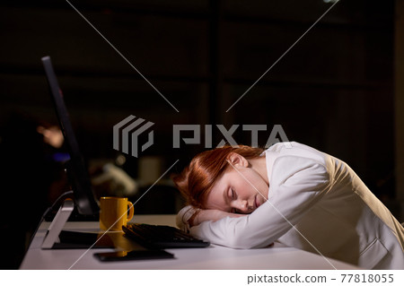 Young caucasian female sleeping at work place in office at night, need more rest Young caucasian female sleeping at work place in office at night, need more rest 77818055