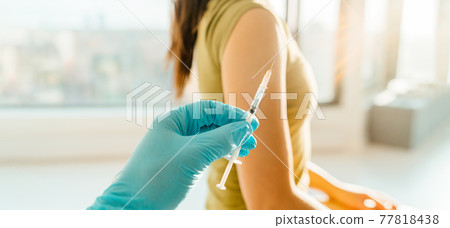 Vaccine against coronavirus at medical clinic banner. Woman being vaccinated with syringe held by healthcare professional worker doctor or nurse giving the shot 77818438