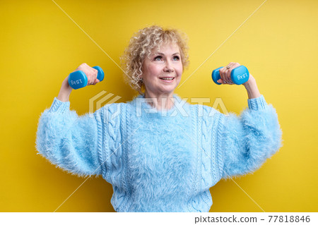 Strong Sportive Senior Woman Lifting Dumbbells Up Isolated On Yellow Background Strong Sportive Senior Woman Lifting Dumbbells Up Isolated On Yellow Background 77818846