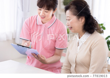 照料者的形象照料高級婦女並填寫調查表的照料者 照料者的形象照料高級婦女並填寫調查表的照料者 77819013