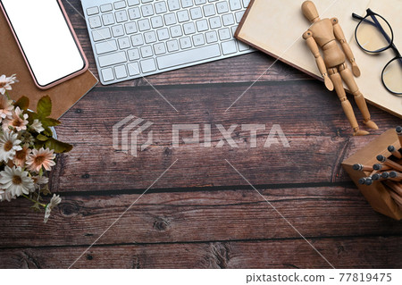 Top view wooden desk with notebook, smart phone, pencil holder, keyboard and glasses. 77819475