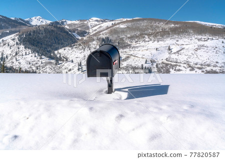 Black freestanding residential mailbox against deep snow in Park City Utah Black freestanding residential mailbox against deep snow in Park City Utah 77820587