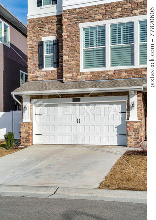 Three storey house with stone brick wall and hinged garage door at the facade Three storey house with stone brick wall and hinged garage door at the facade 77820606