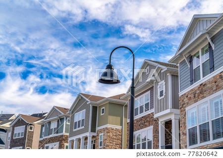 Peaceful town with street light and homes beneath vibrant blue sky and clouds Peaceful town with street light and homes beneath vibrant blue sky and clouds 77820642