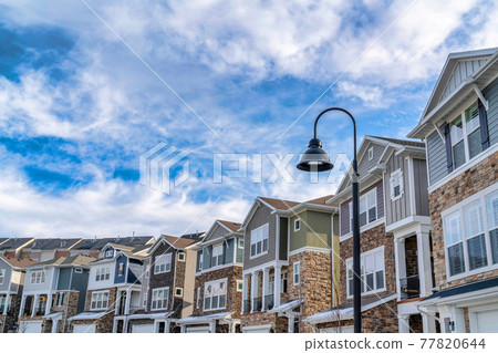 Homes and lamp post against blue sky and clouds on sunny neighborhood landscape Homes and lamp post against blue sky and clouds on sunny neighborhood landscape 77820644