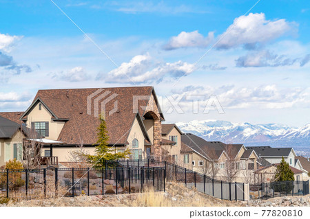Homes in Utah Valley neighborhood against snowy mountain and cloudy blue sky Homes in Utah Valley neighborhood against snowy mountain and cloudy blue sky 77820810