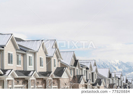 Gabled townhouses with scenic mountain and overcast sky background in winter 77820884