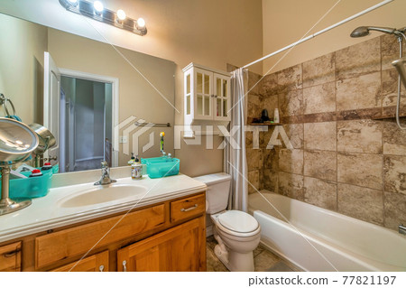 Bathroom interior with bathtub toilet cabinets oval sink and tiles on floor and wall 77821197