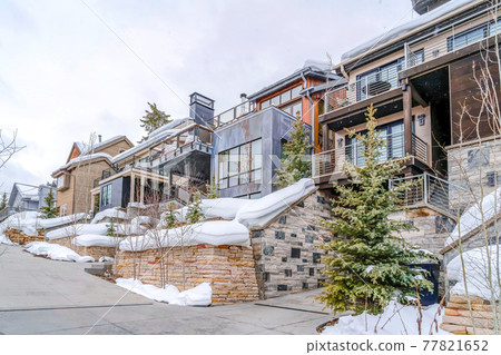 Beautiful family houses with balconies overlooking the snowy neighborhood 77821652