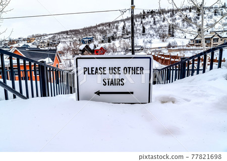 Please Use Other Stairs sign on an impassable stairway in the snowy neighborhood 77821698