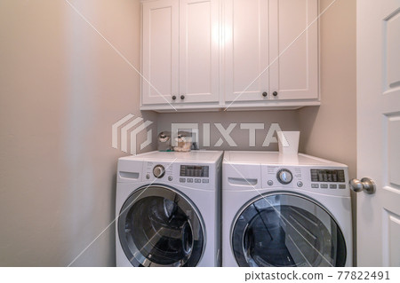 Interior of laundry room with appliances and wall mounted wooden cabinet Interior of laundry room with appliances and wall mounted wooden cabinet 77822491
