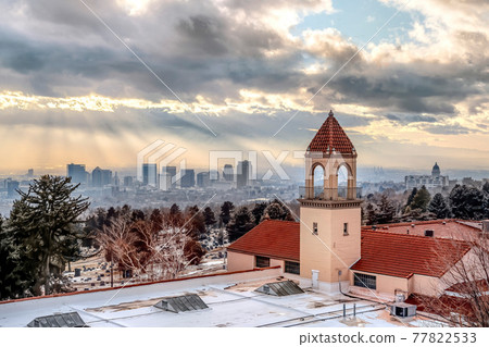 Snowy rooftop with bell tower of a church with Salt Lake City view in the background 77822533