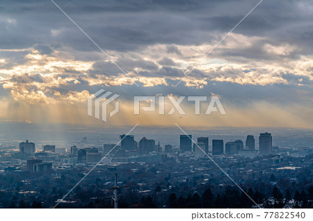 Skyscrapers and buildings on a city landscape with sunlight and overcast sky 77822540
