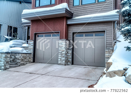 Two car garage with glass paned gray doors at the facade of home in winter Two car garage with glass paned gray doors at the facade of home in winter 77822562