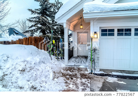 Glass paned door and garage doors of a white home on a snowy mountain town Glass paned door and garage doors of a white home on a snowy mountain town 77822567