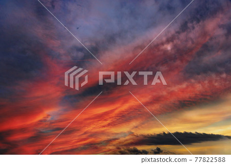 Extremely colorful sunset, with sun rays setting clouds on fire. 77822588