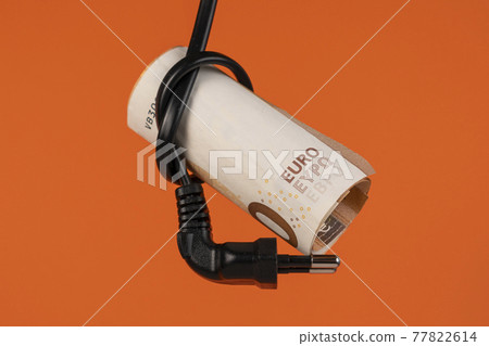 Euro money in an electrical cord knot with a plug close up. Home finance concept. Cash banknotes. On a colored creative terracotta orange background. The savings and high cost of household electricity 77822614