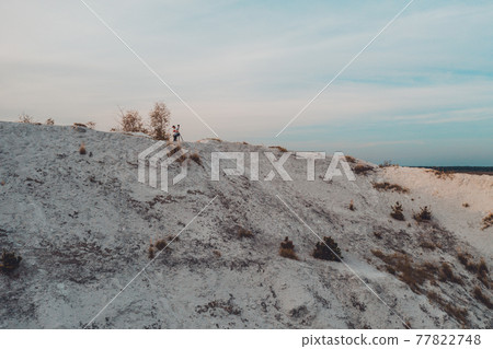 Photographer with a tripod shoots a landscape from the mountain. Phosphate gypsum waste from factories, creating artificial white mountains, attractive tourist view. 77822748