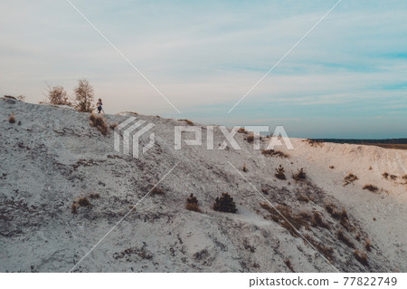 Photographer with a tripod shoots a landscape from the mountain. Phosphate gypsum waste from factories, creating artificial white mountains, attractive tourist view. Photographer with a tripod shoots a landscape from the mountain. Phosphate gypsum waste from factories, creating artificial white mountains, attractive tourist view. 77822749