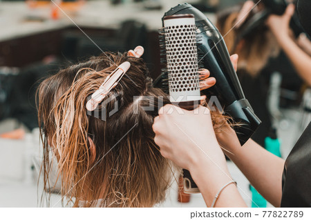 Hairdresser in a mask with at work, drying hair in a barbershop, client and stylist in masks. Hairdresser in a mask with at work, drying hair in a barbershop, client and stylist in masks. 77822789