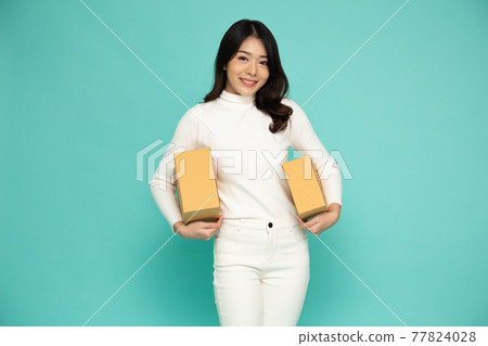 Happy Asian woman smiling and holding package parcel box isolated on light green background, Delivery courier and shipping service concept Happy Asian woman smiling and holding package parcel box isolated on light green background, Delivery courier and shipping service concept 77824028