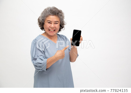 Asian senior woman showing or presenting mobile phone application on hand isolated on white background 77824135