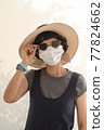 Asian female tourists wear gray clothes, hats, glasses and face masks. 77824662