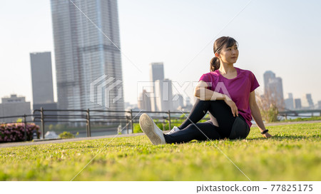 Young woman stretching outside 77825175