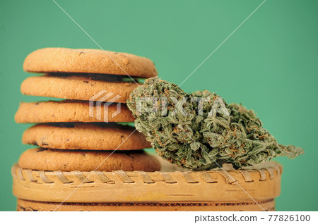 Sweets with CBD oil. Marijuana buds on green background. Sweets with CBD oil. Marijuana buds on green background. 77826100