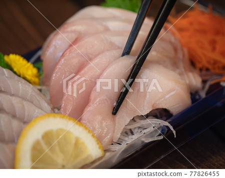Close-up of Spanish mackerel in season in spring. A plastic container containing fresh Spanish mackerel sashimi. 77826455