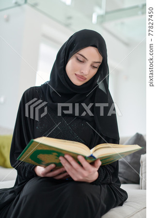 Portrait of young muslim woman reading Quran in modern home 77827450