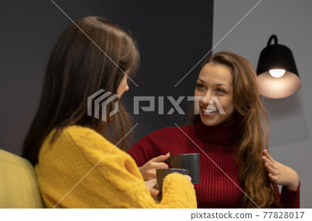 young lesbian couple talking on couch with cup of coffee young lesbian couple talking on couch with cup of coffee 77828017