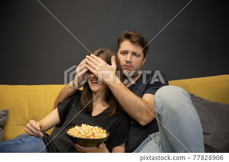 guy covered girlfriend eyes his palms watching TV. bloody thriller Scary moment guy covered girlfriend eyes his palms watching TV. bloody thriller Scary moment 77828906