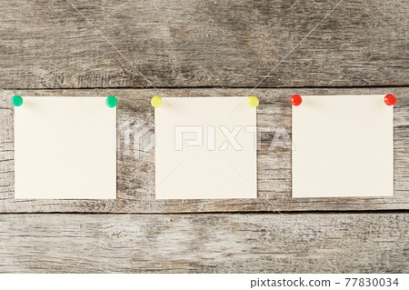 Sticky notes with pins in a row on a wooden background. 77830034